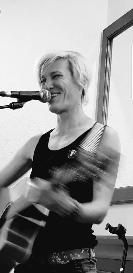 Diane A. souriant sur scène avec sa guitare